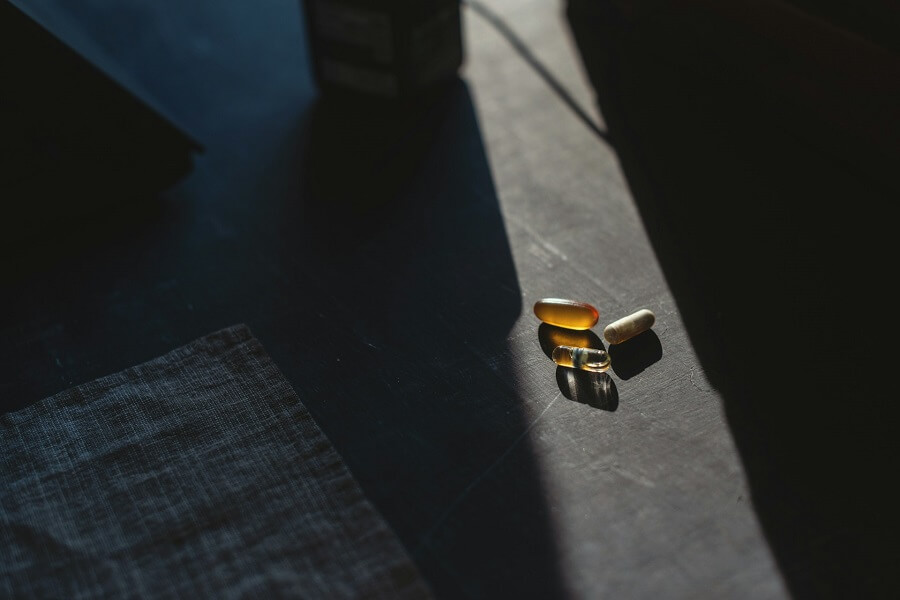 A scoop of gut health probiotic powder beside a glass of water in natural light, a strain-named daily supplement