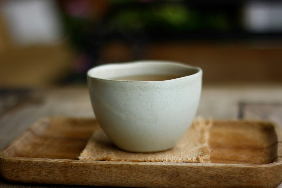 Loose herbal tea on a wooden spoon in kitchen window light, single-purpose Hormonal Health cycle support