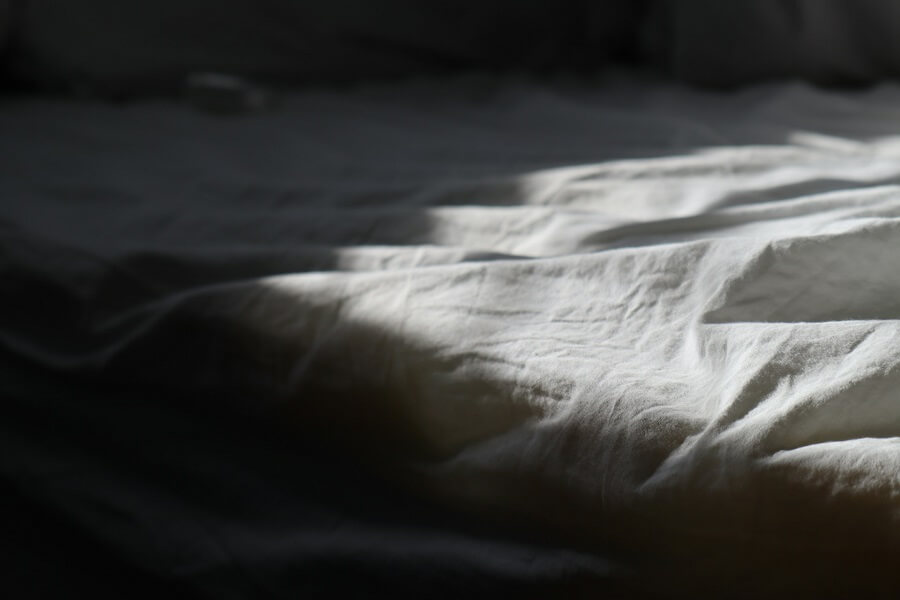 Rumpled linen bedsheets in early morning light, sleep as a free Hormonal Health habit