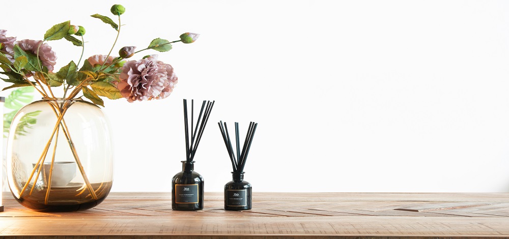 A reed diffuser with rattan sticks on a shelf in soft daylight, natural home fragrance