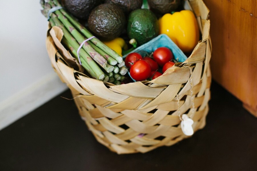 A grocery basket of vegetables and staples in daylight, eating well on a budget for Eat Well