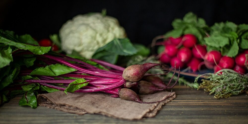Vegetables and grains in bowls on a wooden table in daylight, how to eat well with whole foods